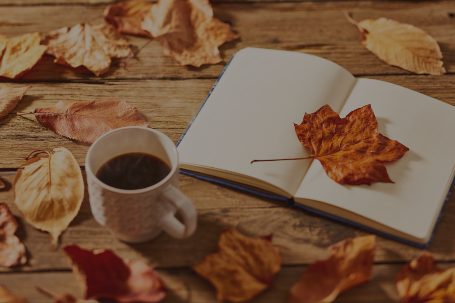 Fall leaves surrounding a journal and cup of coffee