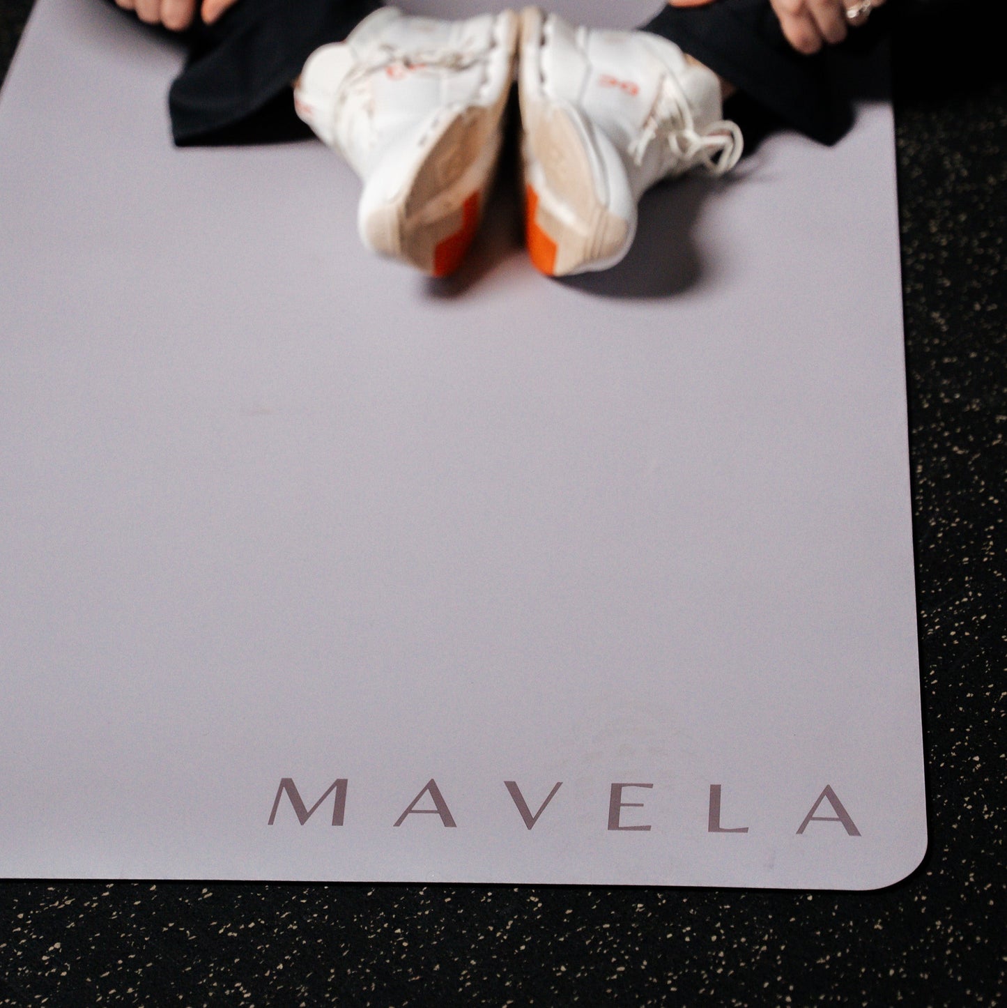 Person stretching on a Mavela yoga mat with white sneakers.